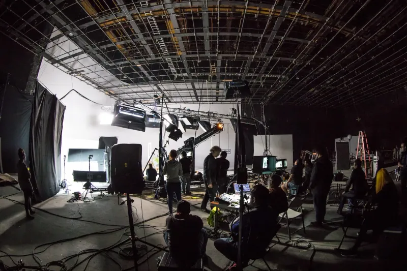 Film set with a lot of lighting and gear as well as crew members.