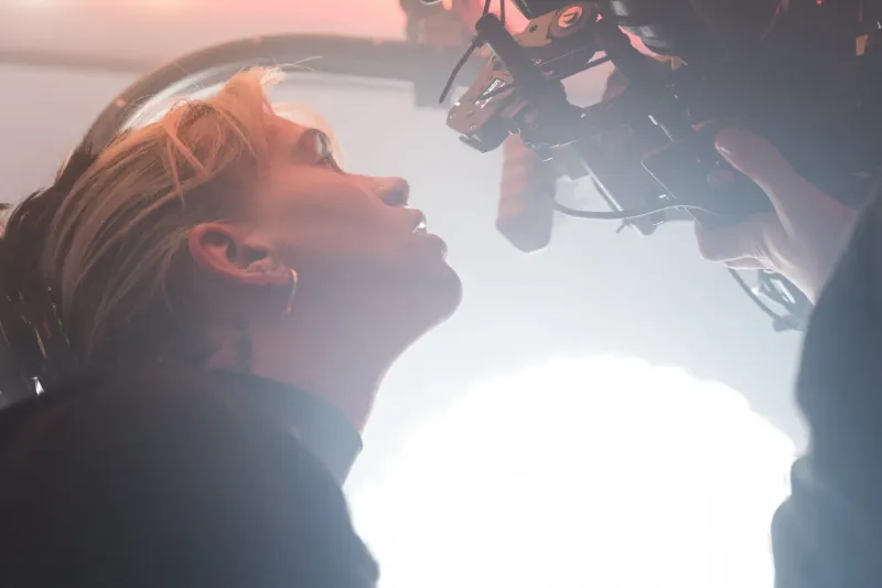 Closeup back light, person looking through a camera viewfinder.